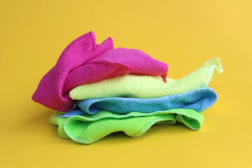 A bunch of different bright multi-colored napkins for cleaning lie on a yellow background.	