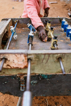 Crop African kid playing mini football on foosball table