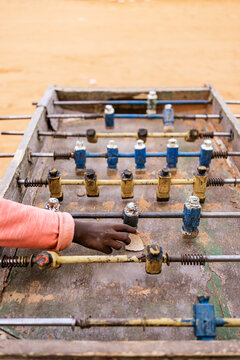 Crop African kid playing mini football on foosball table