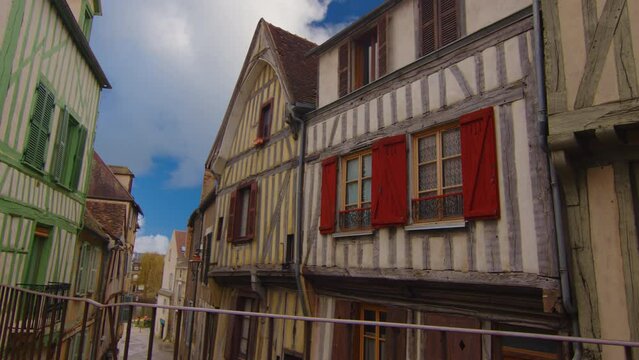 Classic medieval French facades of houses and hotels in the center of the old city not far from Paris against the backdrop of a blue sky and blue clouds. Colored buildings of old houses in France
