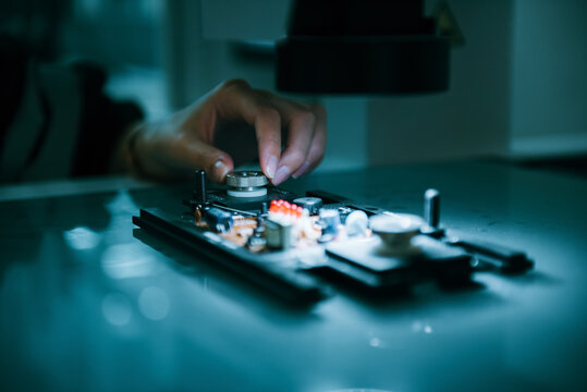 Close Up On Specialist Engineer Using Small Machine For Controlling And Testing New Programing On Circuit Board For Micro Robotic Arm Welding. Technician Maintenance Working In Microchip Industry.