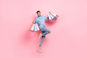 Full length photo of glad man client customer wear trendy blue clothes hold bags rejoice nice purchases isolated on pink color background