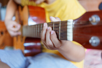 Close-up of white boy's hands holding guitar chords