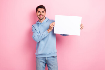 Photo of pretty cool guy dressed blue sweatshirt rising white poster empty space isolated pink...