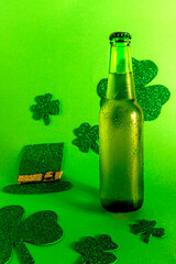 Green cold beer bottle on green background with shamrock and sombrero, st patrick's day vertical