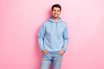 Photo of charming cheerful guy dressed blue sweatshirt smiling arms hands pockets isolated pink...