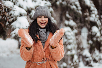 Pretty young long-haired woman in pink coat enjoy winter day at snowy park