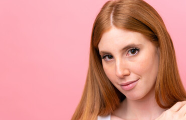 Young redhead woman isolated on pink background