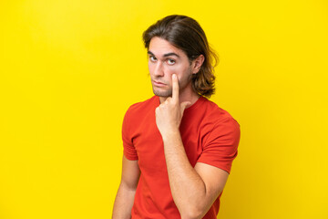 Caucasian handsome man isolated on yellow background showing something