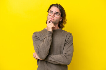 Caucasian handsome man isolated on yellow background having doubts and thinking