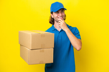Delivery handsome man isolated on yellow background looking to the side and smiling