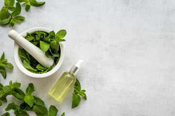Peppermint essential oil in bottle with fresh mint leaves