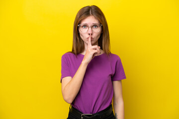 Young English woman isolated on yellow background showing a sign of silence gesture putting finger in mouth