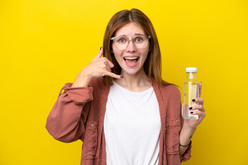 Young English woman with a bottle of water isolated on yellow background making phone gesture. Call me back sign