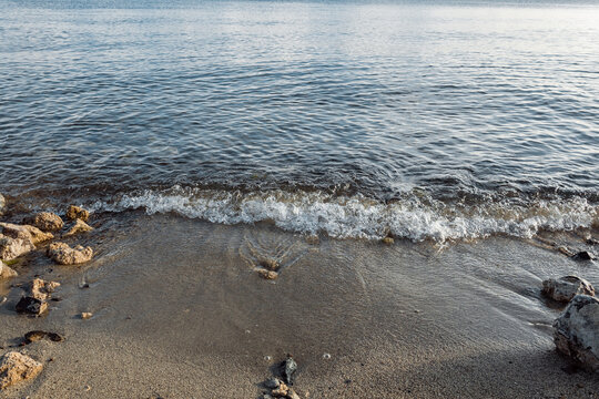 The shore of the reservoir. Sandy beach of a mountain lake with stones.