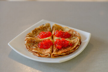 Pancakes. Shrovetide. Pancakes on a white plate. Pancakes with red caviar. Delicious pancakes. Russian pancakes. Delicious dessert. Dinner. Breakfast. Red caviar. Tasty dish