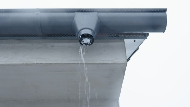 gutter with flowing rainwater on the roof of the building