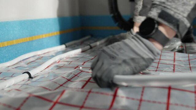a worker installs underfloor heating in a new building