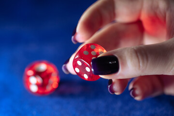 Red casino dice in female hand. A woman plays dice