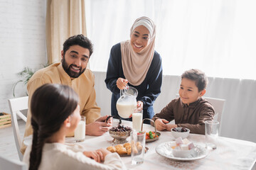 Obraz na płótnie Canvas Smiling muslim family looking at daughter during suhur breakfast at home.
