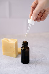 Frasco con cuentagotas para aceites esenciales en aromaterapia, con jabón artesanal en baño.