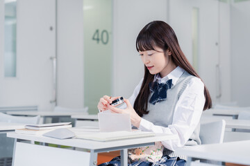 学校でメイクをする女子高生