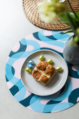 Cross bun and chocolate easter egg with eggs on a white plate