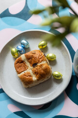 Cross bun and chocolate easter egg with eggs on a white plate