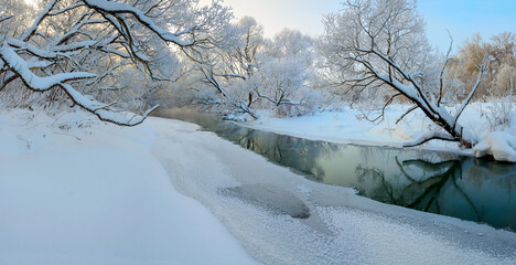 Winter frosty panoramic landscape with forest river and snow covered trees in calm december morning