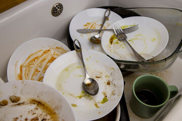 A pile of unwashed dishes in the sink. Mess and dirt in the kitchen. Dirty plates, mugs and cutlery. Putting the house in order, big cleaning, cluttered house