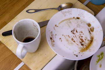 A pile of unwashed dishes in the sink. Mess and dirt in the kitchen. Dirty plates, mugs and cutlery. Putting the house in order, big cleaning, cluttered house