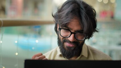 Happy executive Indian bearded entrepreneur man in glasses celebrate win with laptop achievement talk video call shout with success. Arabian businessman winning business goal achieve online victory