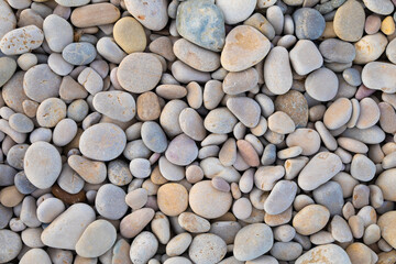 Background texture of rounded stones of various shades and pastel colours on a Mediterranean beach in Spain