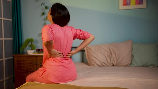 Back view shot of young girl suffering from back pain on bed during sleep at night - concept of exhausted, mattresses Problem and injury