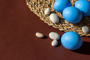 Easter blue eggs with sea pebbles on a brown background.