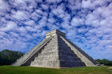 Fototapeta na wymiar Chichén Itzá pyramid ruins, with blue sky with white clouds, Yucatán in Mexico. Traveling in central America. Maya history in Mexico. Chichén Itzá without people.