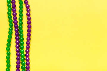 purple and green beads on yellow background Top view 2022 Mardi Gras Parade Schedule Mockup Copy...