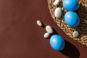 Easter blue eggs with sea pebbles on a brown background.