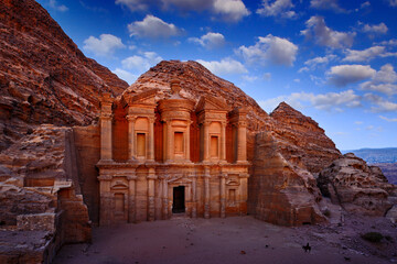 Travel in Jordan, Arabia in Asia. Stone Monastery in rock, Petra in Jordan. Red rock landcape. Petra historical sight - Ad Deir Monastery with blue sky and white clouds. Evening light in nature.