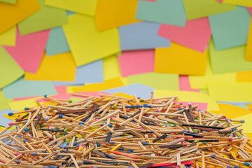 matchsticks of various shapes and colors with multicolored paper sticky notes on background