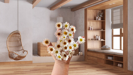 Woman's hand holding daisies, spring and flowers idea, over japandi wooden bathroom in boho style. Bathtub and window with bench. Bohemian interior design