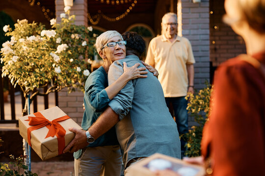 Happy senior woman embracing her son who came for family visit with his wife.