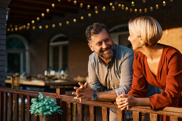 Happy couple talks while enjoying on terrace.