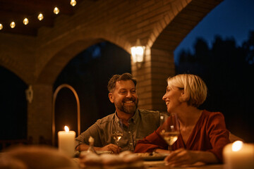 Happy couple enjoys in glass of wine in evening on terrace.