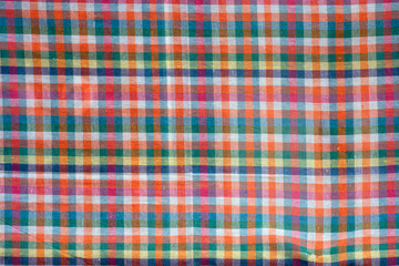 Colorful checkered tablecloth as background, top view.