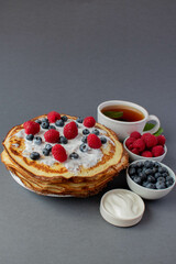 french pancakes with berries and a cup of mint tea