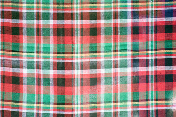 Colorful checkered tablecloth as background, top view.