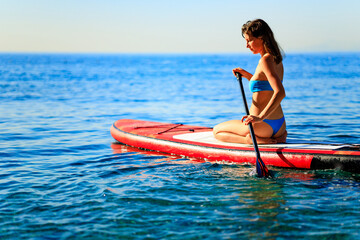 Woman sitting on sup board and enjoying peace and quiet outdoors