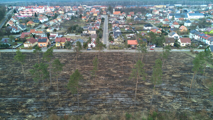 Aerial view above damaged nature at a deforestation area. Small town in the background. New land for new houses, drone shot.