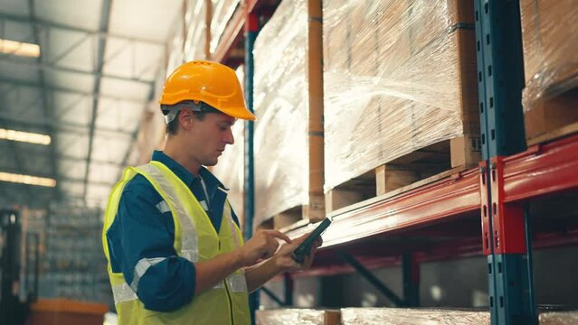 Man worker checks products stock inventory with digital tablet in the retail warehouse full of shelves Male employee wearing hard hat doing work in storehouse.